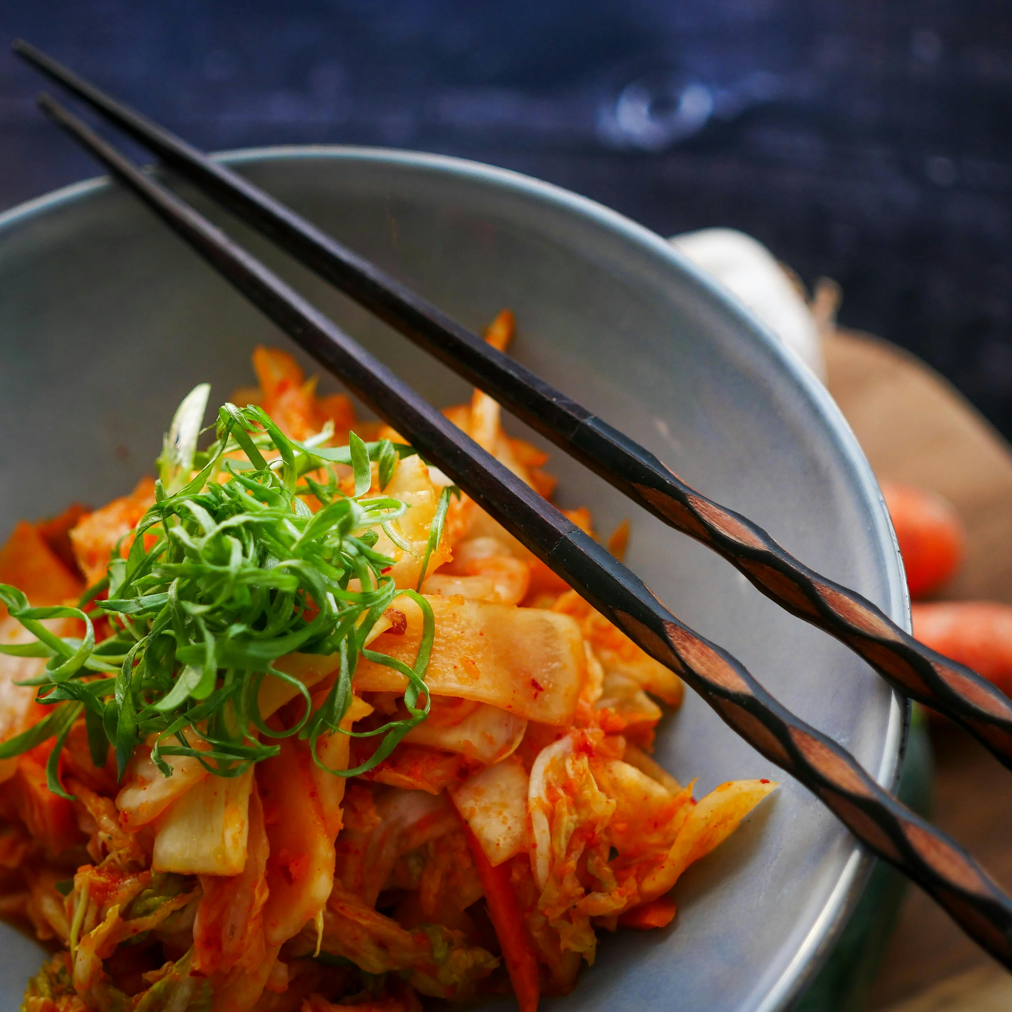 Kimchi in a bowl with chopsticks and garnish
